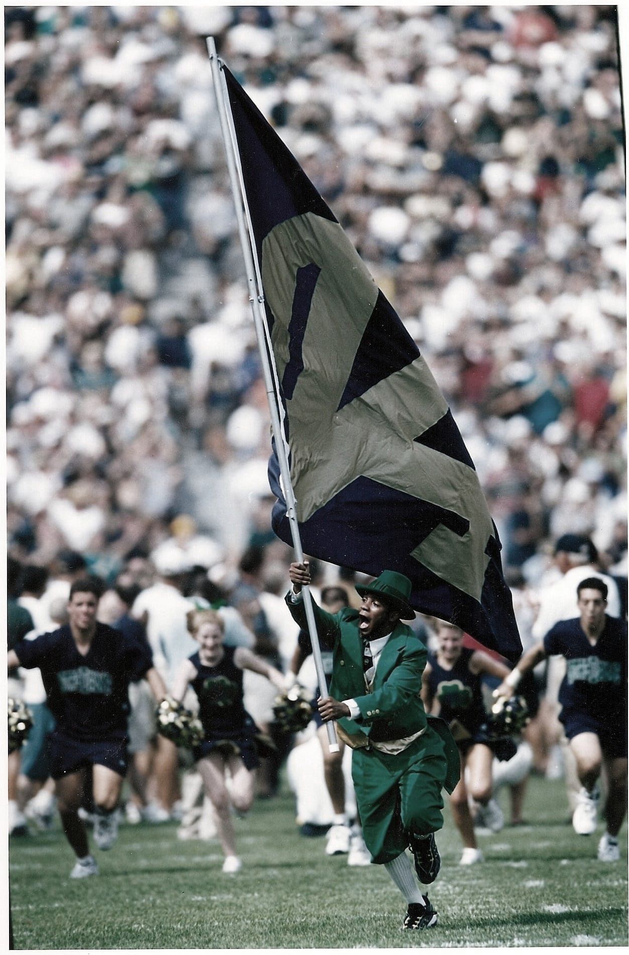 Mike Brown as the Notre Dame Leprechaun, sprinting onto the field carrying the Notre Dame flag as the team runs out behind him